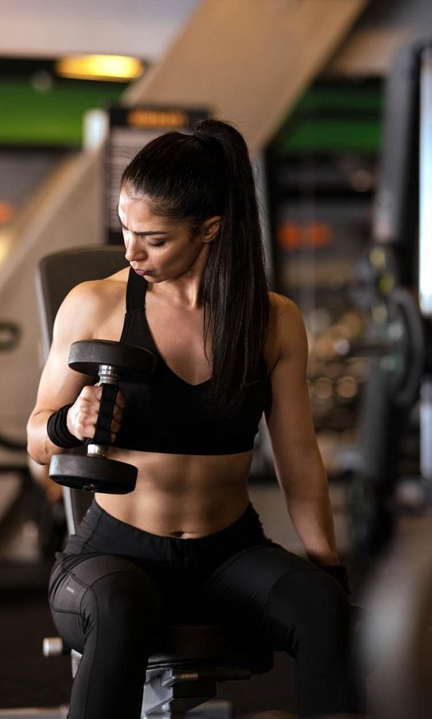 Mujer realiza ejercicio con pesa mancuerna.