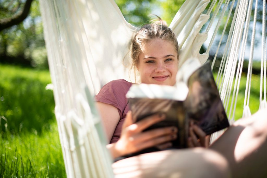 Adolescente leyendo un libro en una hamaca