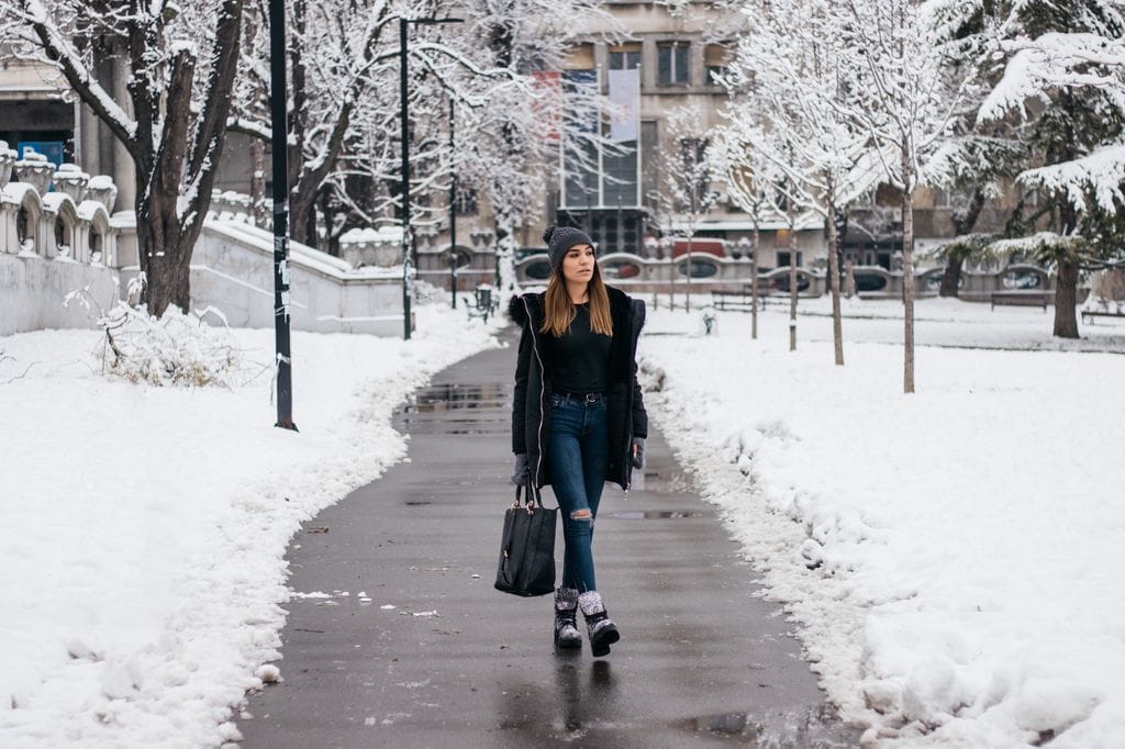 Mujer caminando por la ciudad con nieve