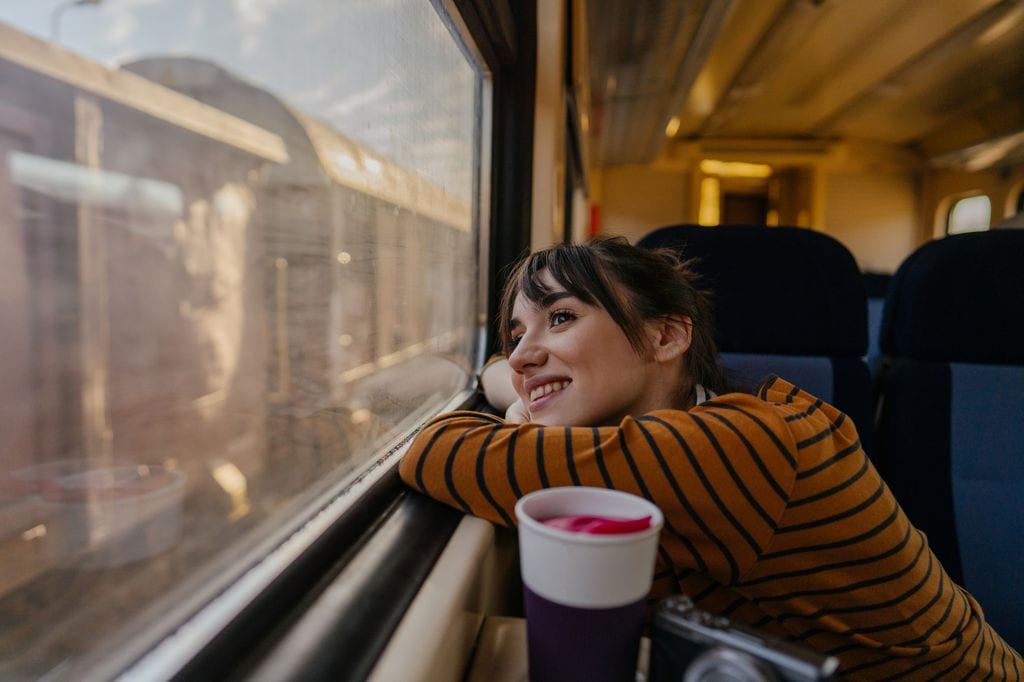 Mujer feliz mirando por la ventana mientras viaja en tren