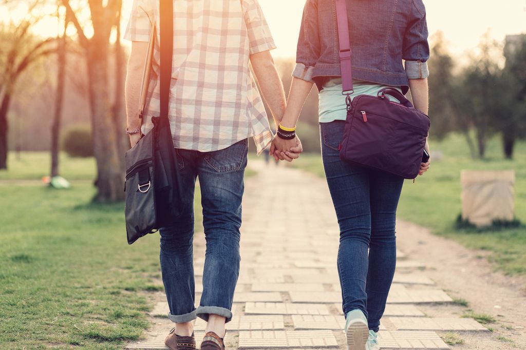Pareja adolescente de la mano, vistos de espaldas