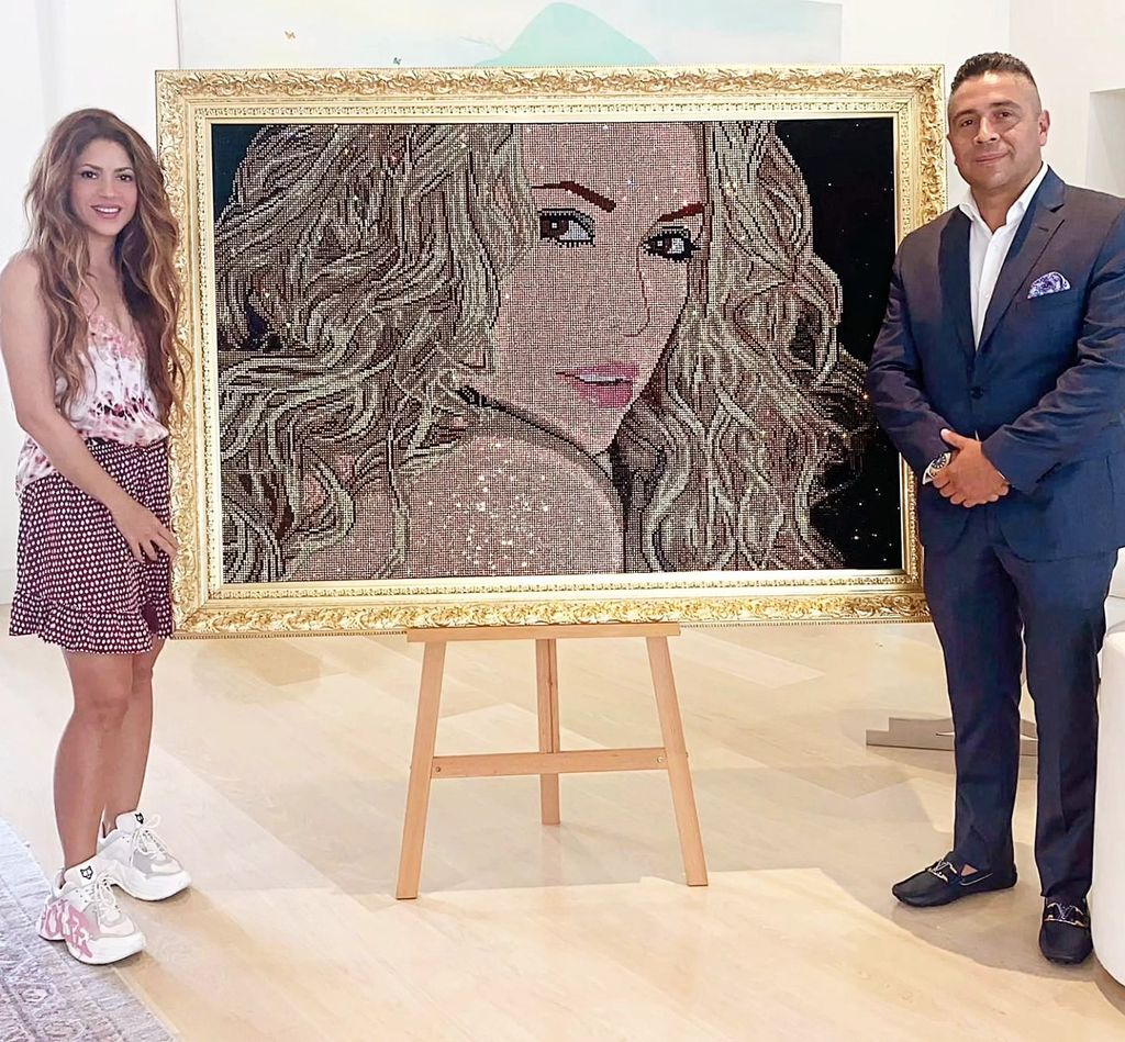 Shakira y Mr. Bling posan juntos al lado de la obra en honor a la cantante