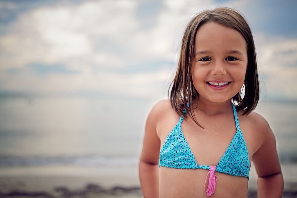 Niña con un traje de baño azul en la playa