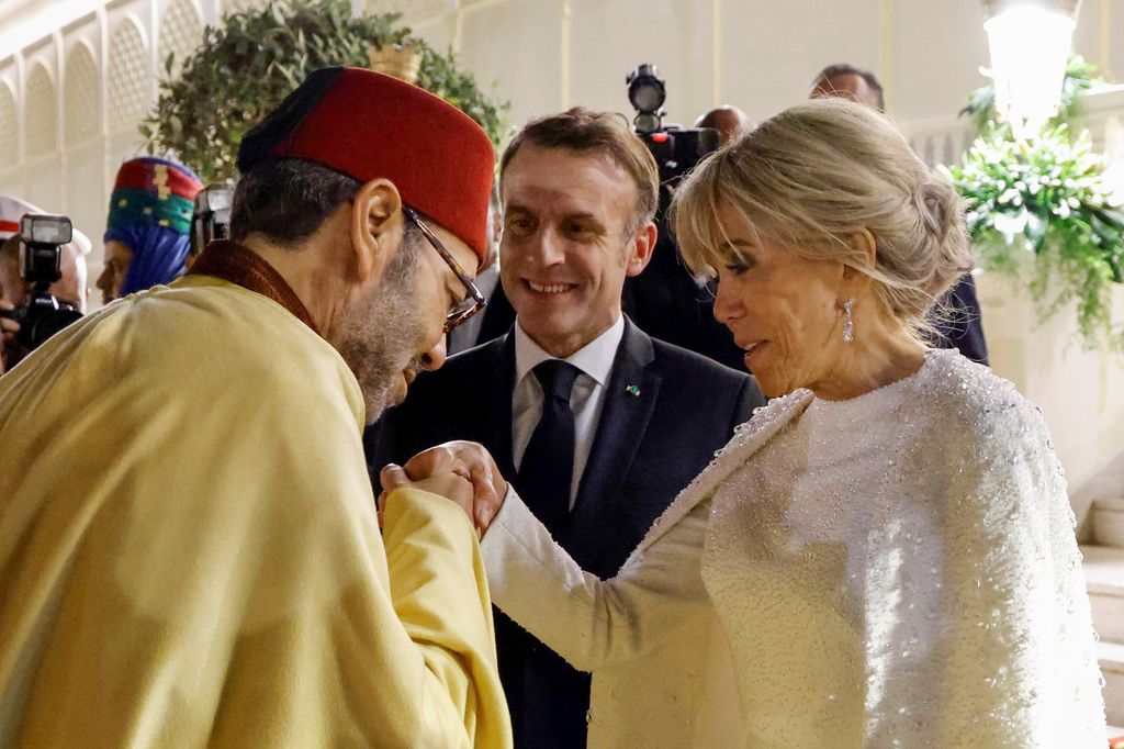 Plano medio de Emmanuel y Brigitte Macron saludando a Mohamed VI en una cena de Estado