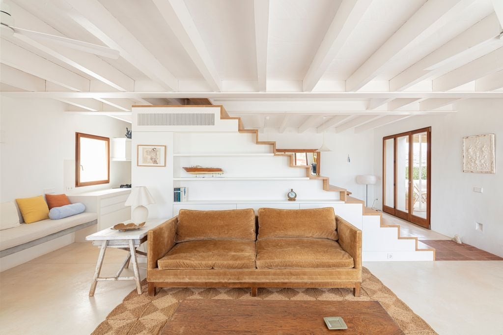 Salón con sofá marrón delante de escalera
