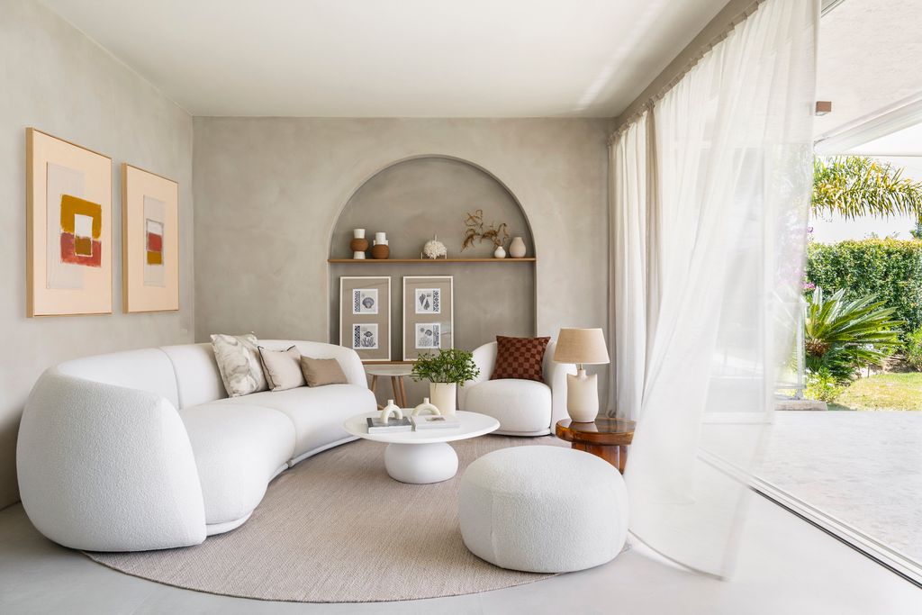 Salón en tonos claros y sofá de líneas curvas. 