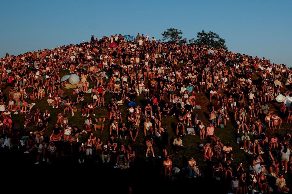 Cientos de personas se concentran en una zona elevada de Madrid, prácticamente sin dejar un hueco libre, para seguir el eclipse con sus gafas de protección.