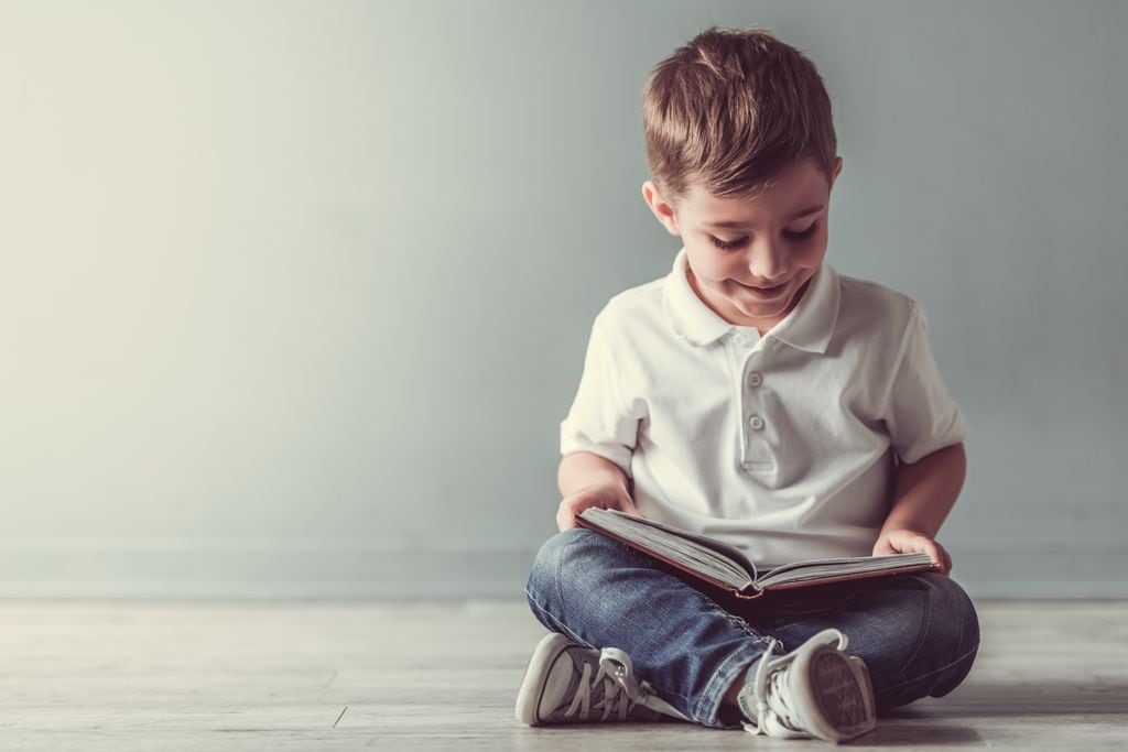 Niño leyendo un libro sentando en el suelo