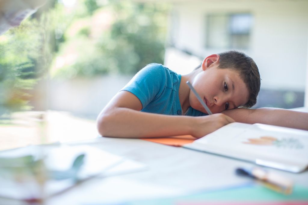 Niño cansado sobre la mesa de estudio