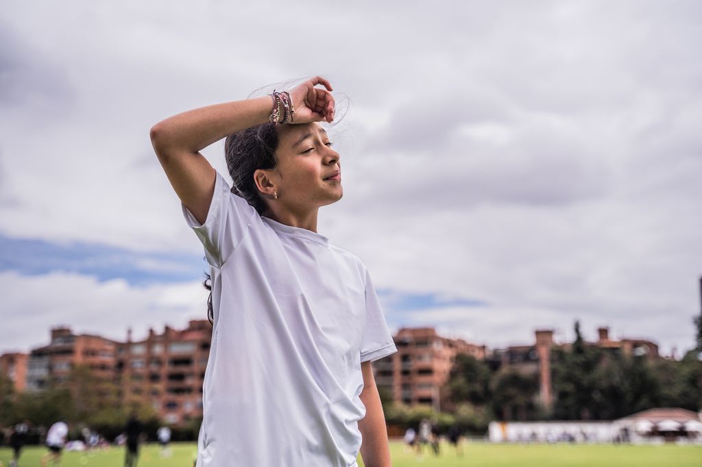 Niña con síntomas de calor con la mano en la frente
