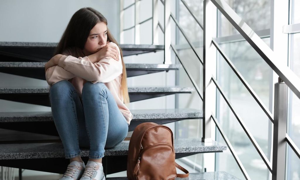 chica adolescente melancolica mirando por la ventana sentada en unas escaleras