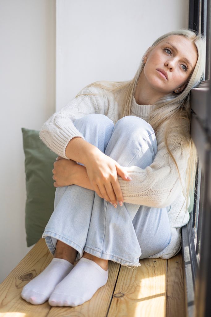 Mujer triste apoyada en una ventana