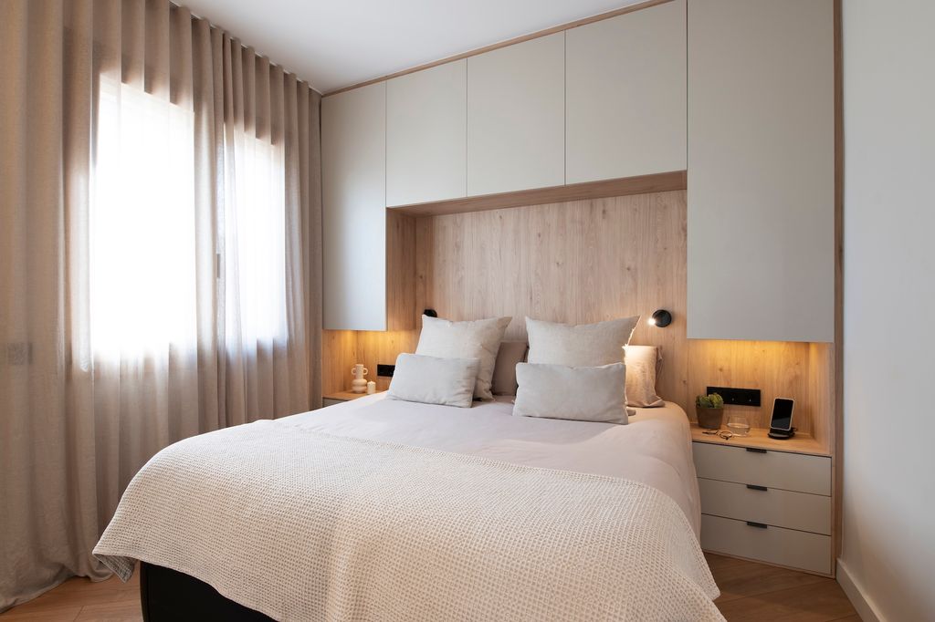 Dormitorio con mueble tipo puente en la pared del cabecero.
