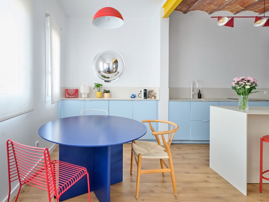 Una mesa redonda crea un espacio de reunión junto a esta cocina abierta y llena de color