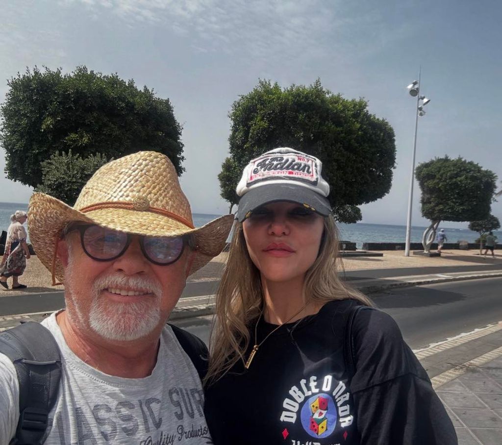 Hombre y mujer con sombreros, junto al mar. Él con barba, ella con cabello largo.
