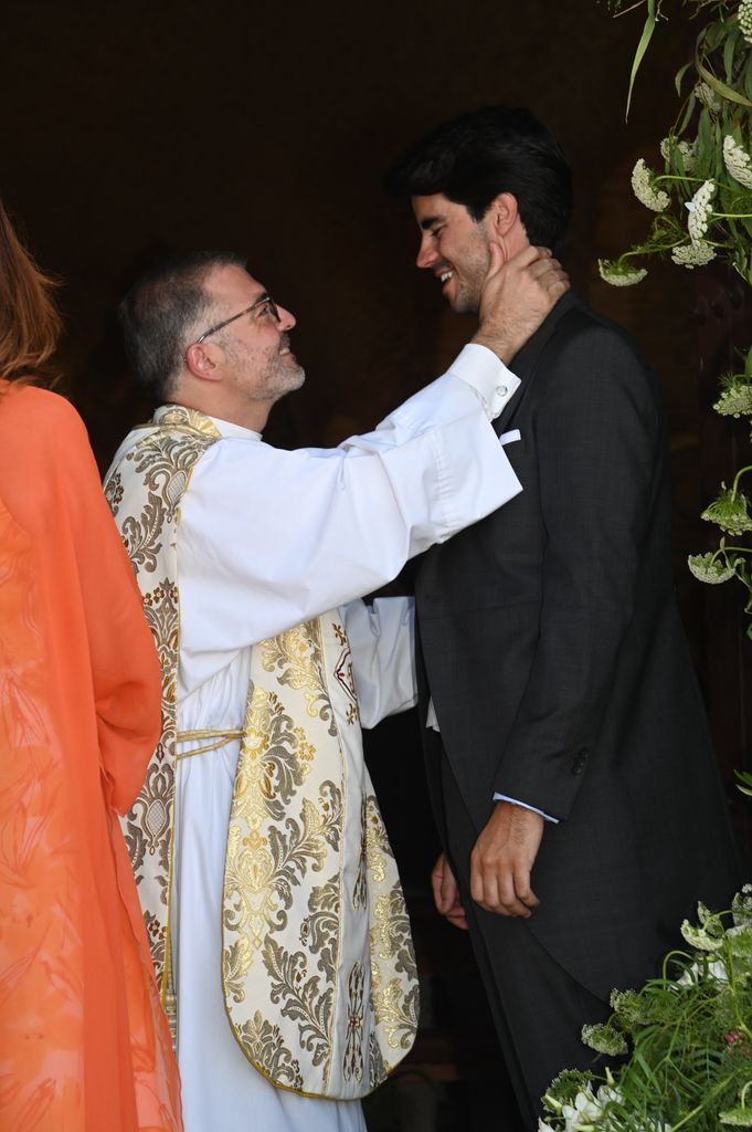 El sacerdote que ha oficiado la ceremonia saluda al novio