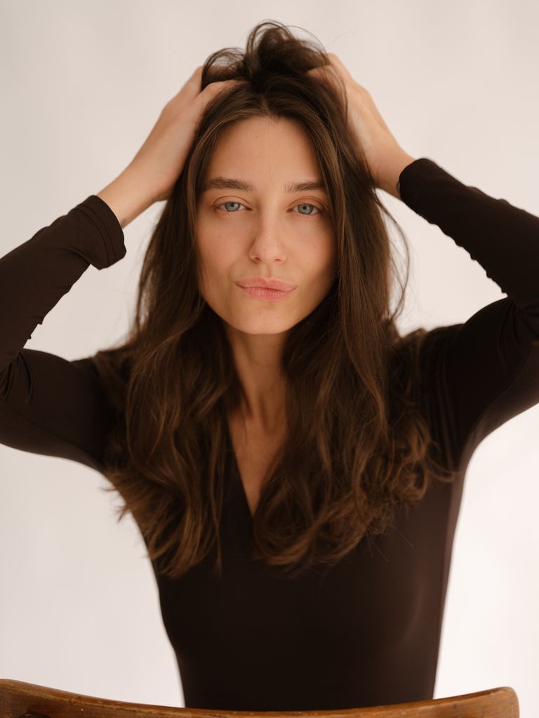 Rostro de mujer sonriente con las manos en la cabeza levantándose el cabello