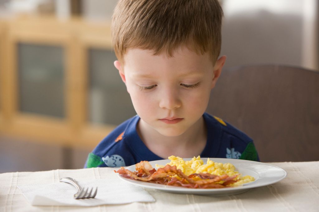 Niño delante del plato con actitud de no querer comer