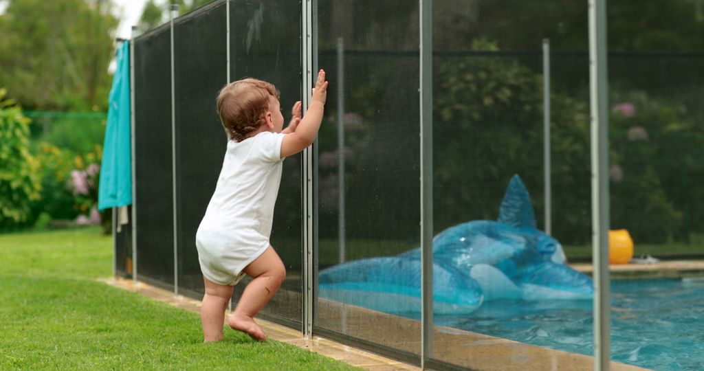 Bebé tras una valla de seguridad en una piscina para evitar ahogamientos
