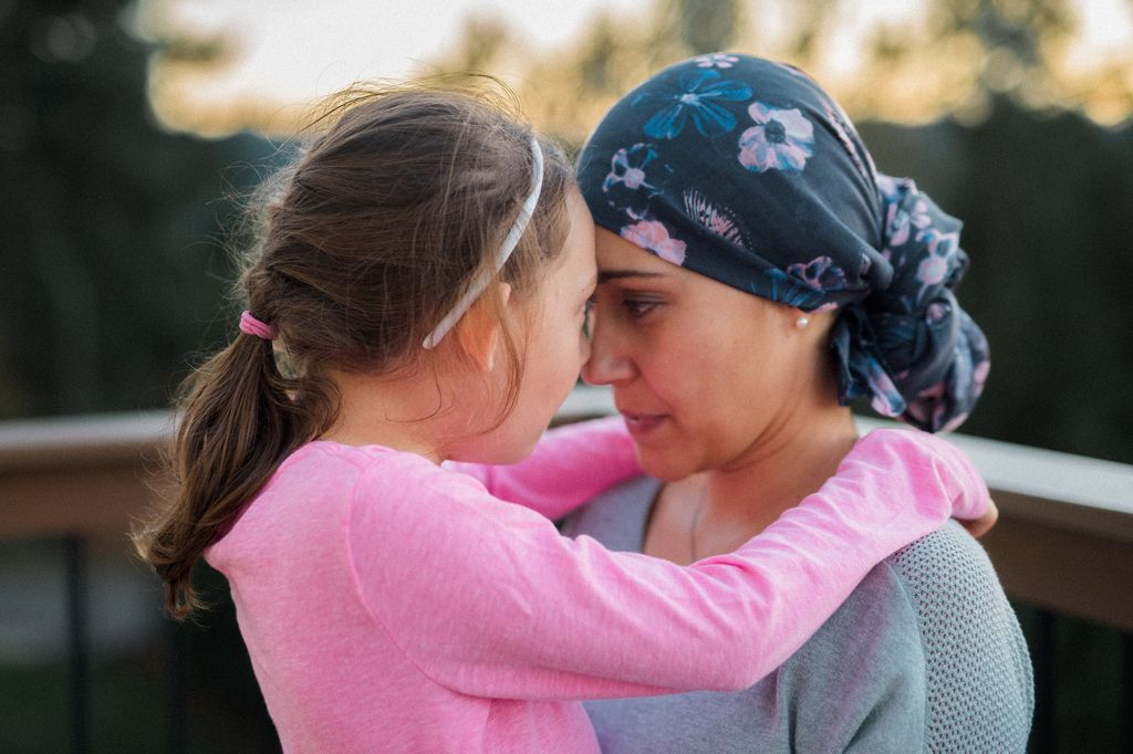 Madre con cáncer de mama abrazando a su hija pequeña