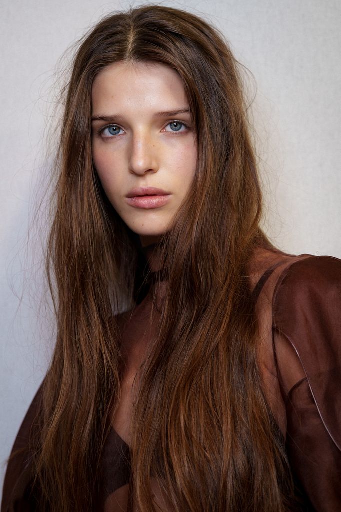 Modelo en el backstage de Aje con el pelo suelto y castaño pero con cazadora marrón
