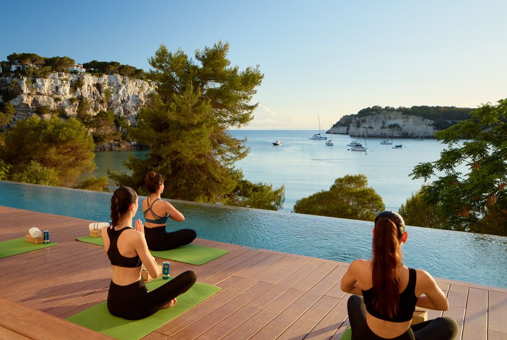Clase de yoga mirando al mar, junto a la piscina, en el Hotel Meliá Cala Galdana