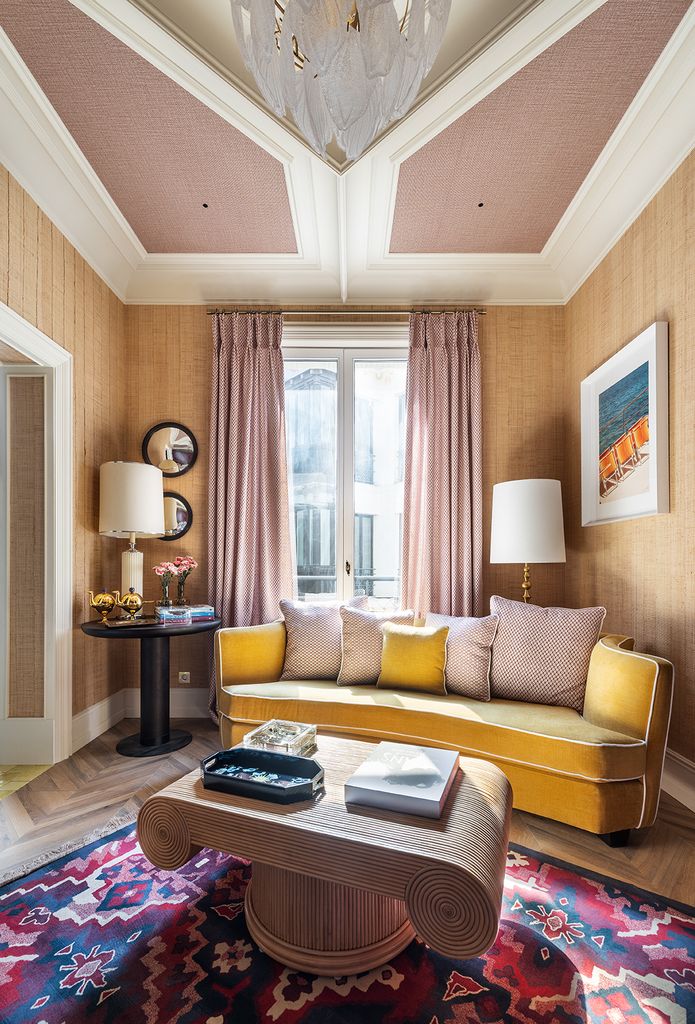 Salón con el techo decorado con papel pintado y sofá amarillo
