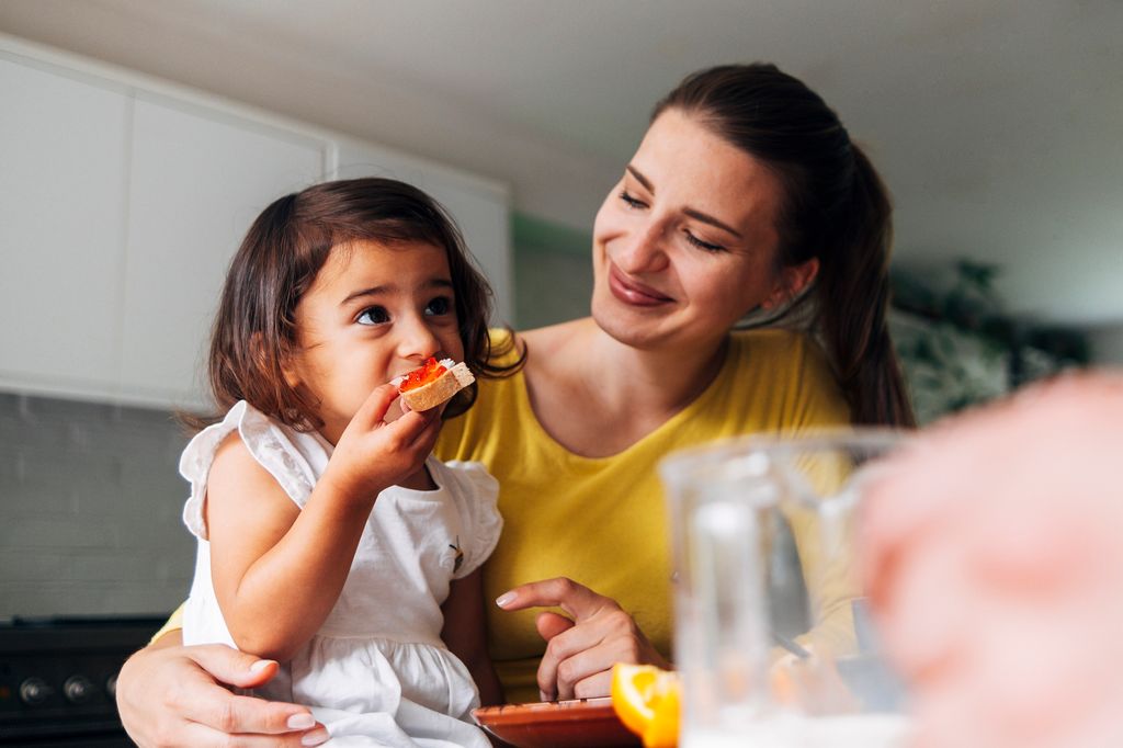 Madre relajada comiendo con su hija pequeña en la cocina