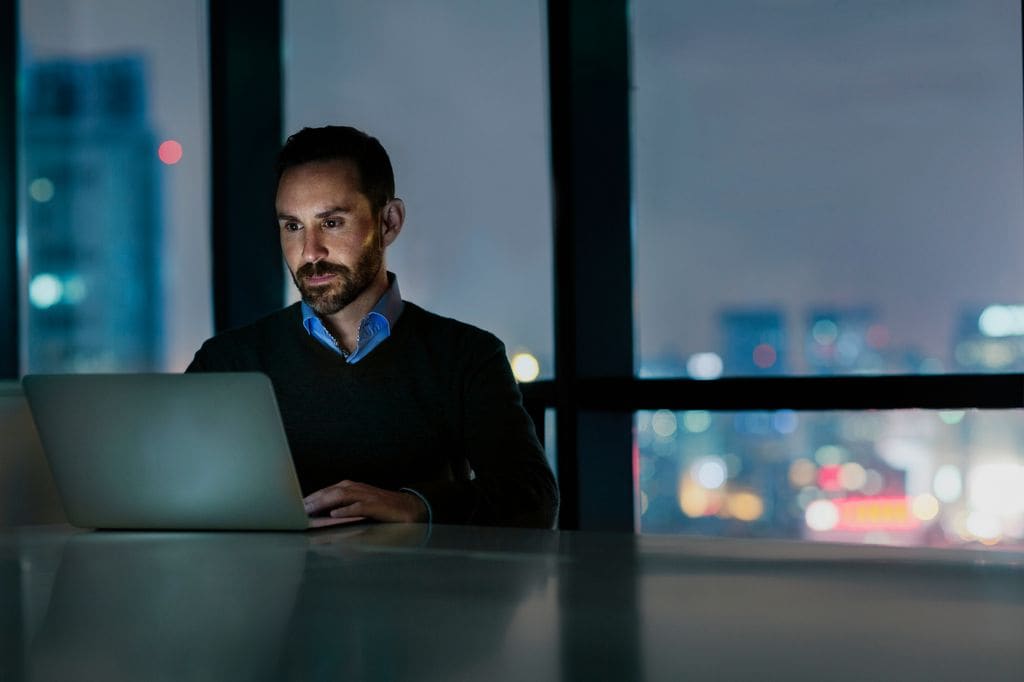 Hombre usando en ordenador de noche en la oficina 