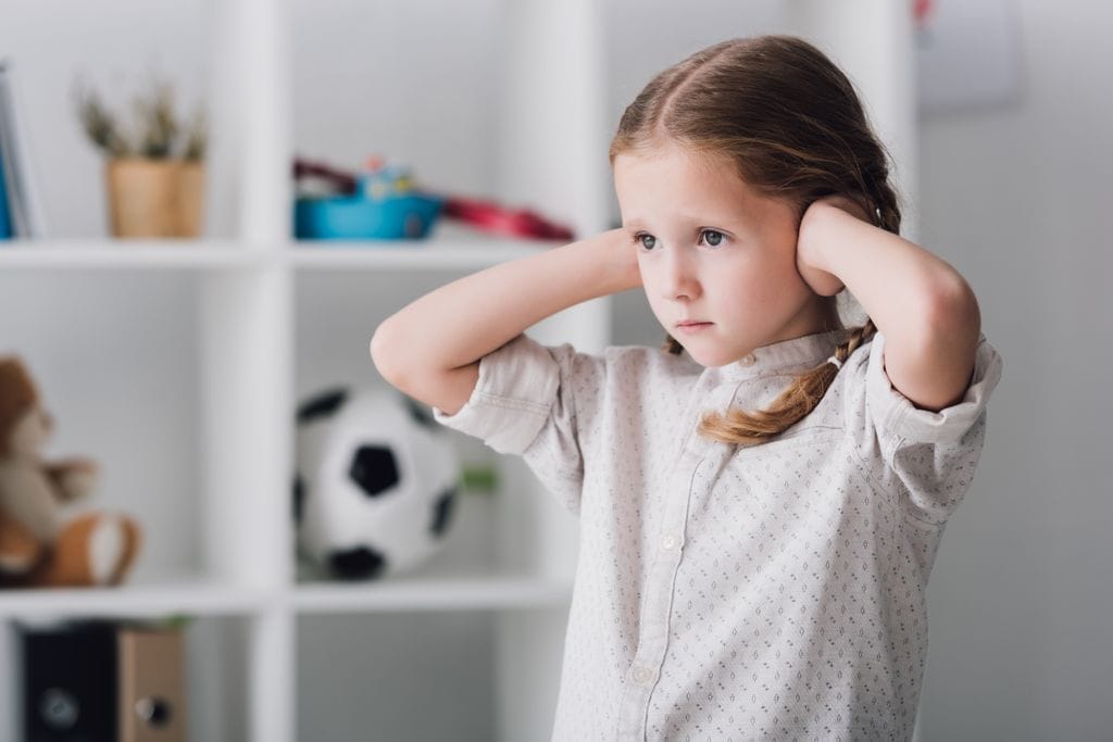 Niña con autismo tapándose los oídos