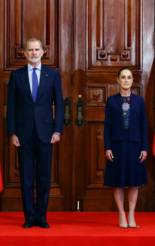 El rey de España y la presidenta de México, escuchando atentos los himnos nacionales de sus países. 
