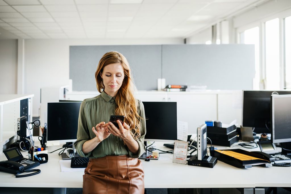 mujer en la oficina mirando su móvil