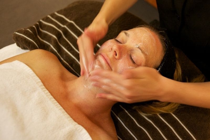 Esteticista realizando exfoliacion al rostro de una mujer