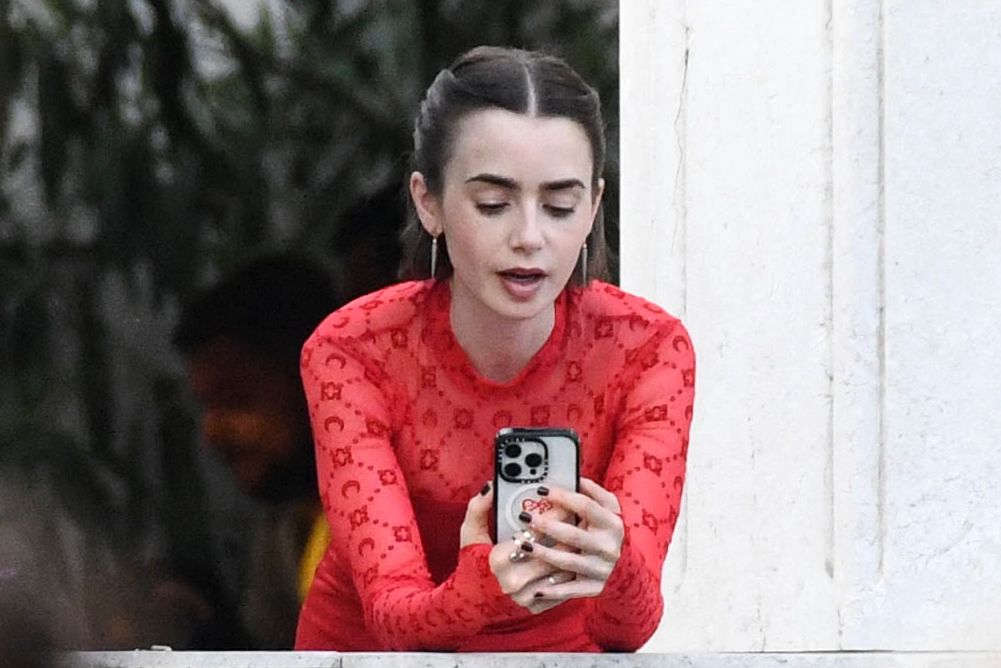 Actress Lilly Collins takes advantage of a break from filming Emily in Paris at the Palazzo Franchetti to connect with her loved ones via FaceTime. Venice, Italy on 16 August 2025