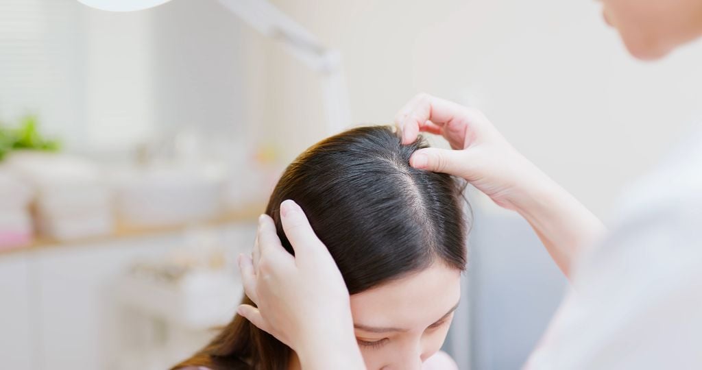 dermatólogo examinando el cuero cabelludo de una paciente