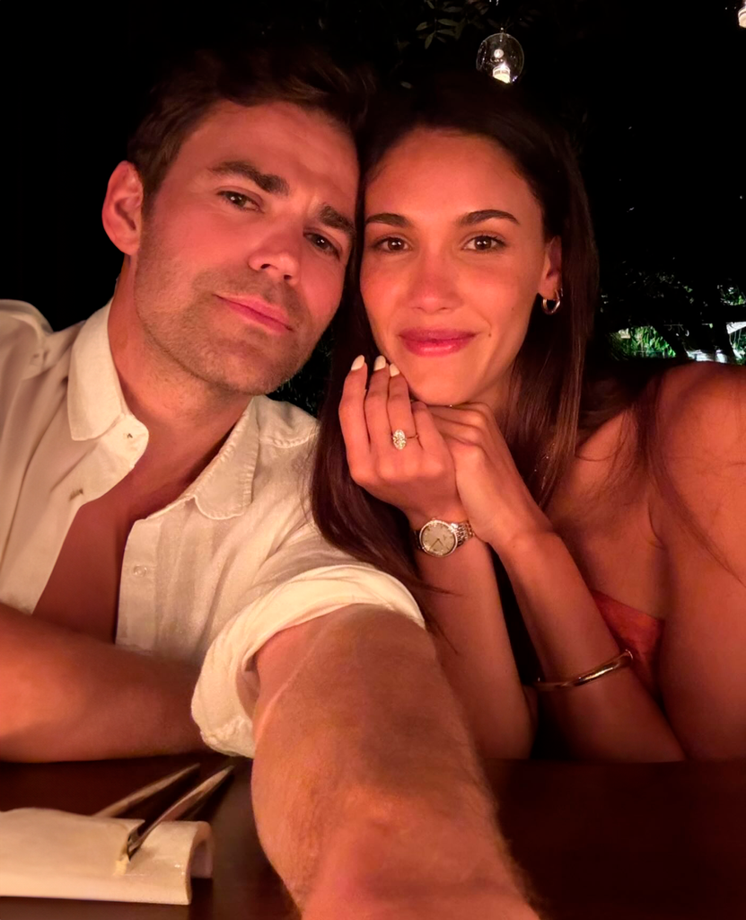 Paul Wesley y una mujer en un restaurante, ambos sonrientes y posando para una foto.
