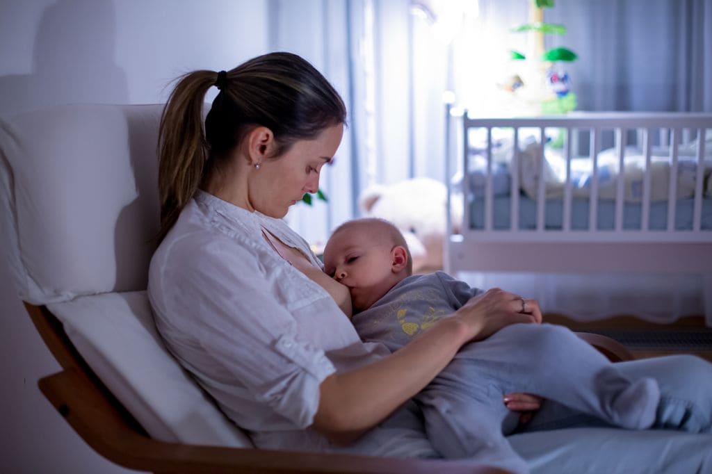 Madre dando el pecho a su hijo por la noche