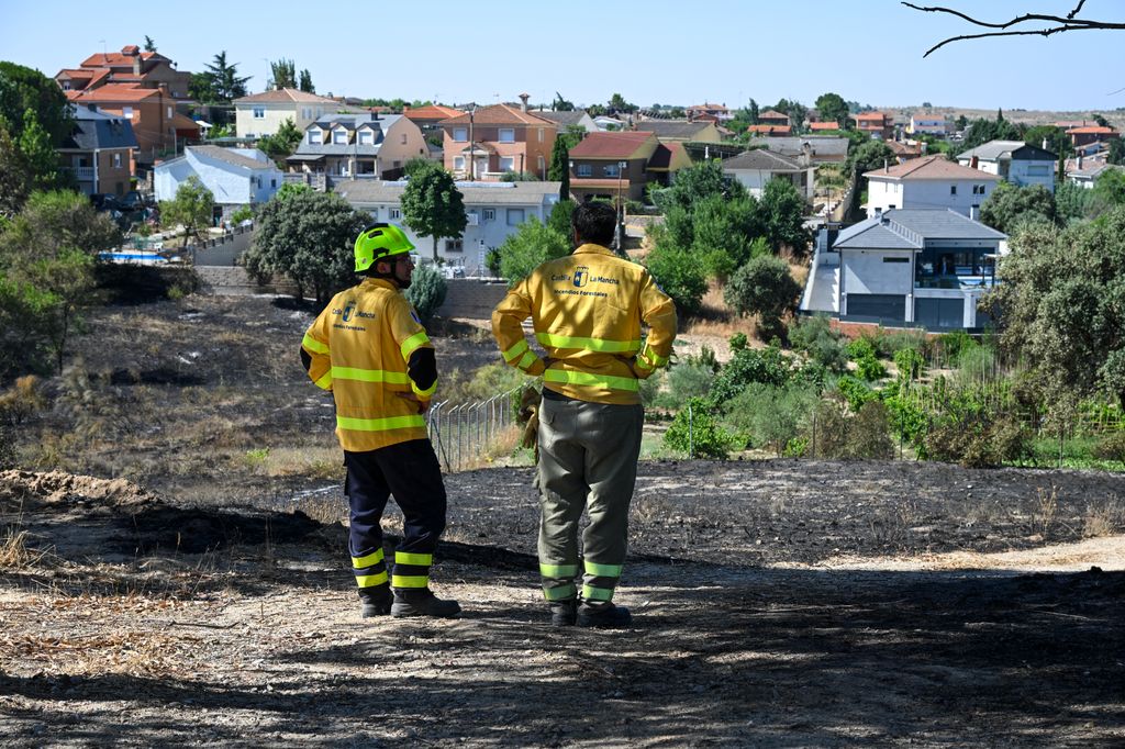 Los bomberos de emergencia se encuentran cerca de las zonas quemadas que rodean la urbanización Calypo Fado tras un incendio forestal que se desató en el municipio de Mentrida, cerca de Toledo
