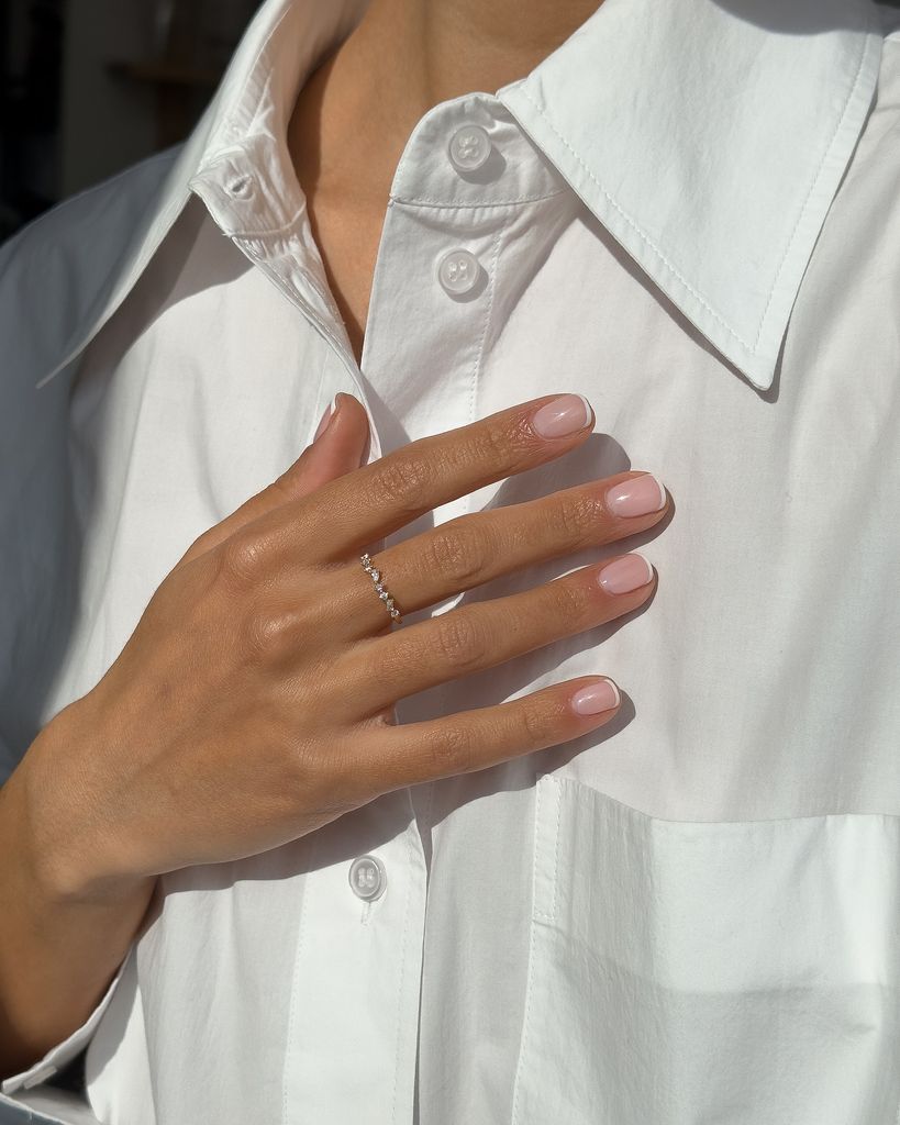Andréa Barbet con camisa blanca y manicura francesa