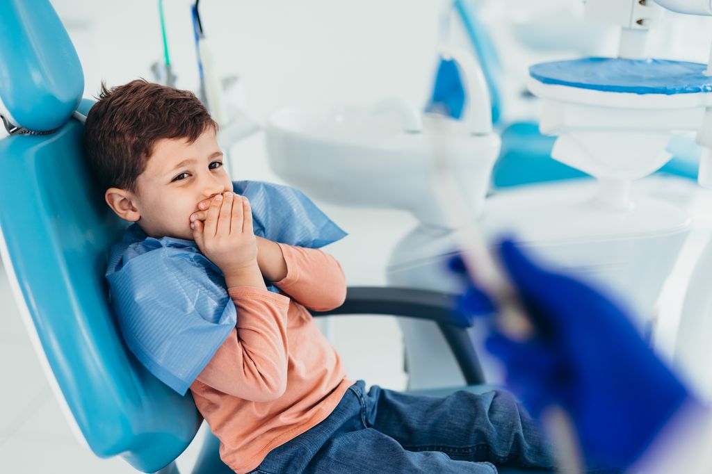 Niño con miedo cerrando la boca en la consulta del dentista