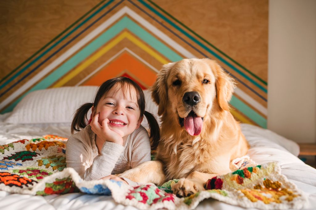 Niña feliz con su perro en la cama
