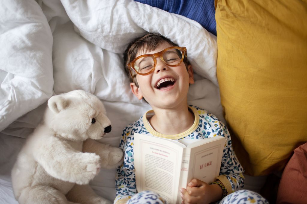 Niño feliz leyendo un libro en la cama