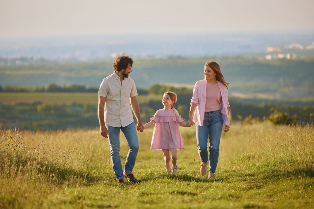 Padres paseando por el campo con su hija