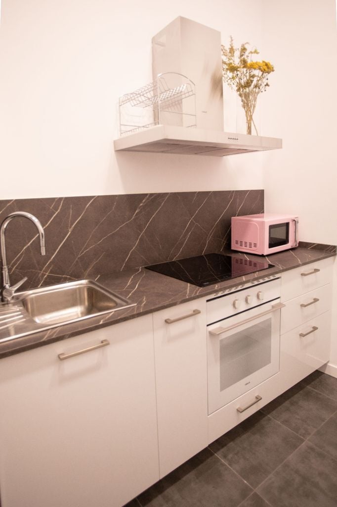 Cocina con muebles blancos y encimera negra