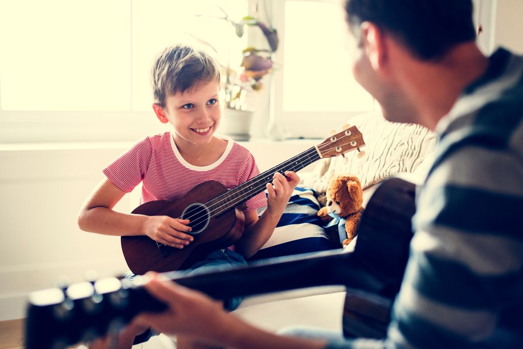Un niño tocando la guitarra con su padre