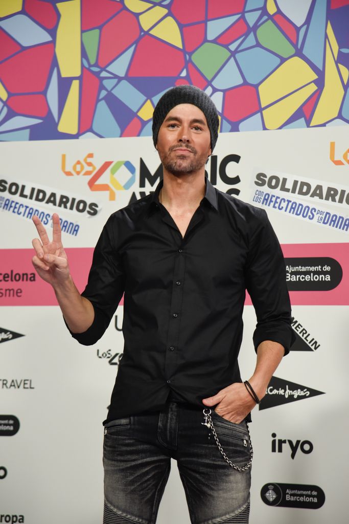 Plano medio de Enrique Iglesias con camisa negra y jeans negros con cadena