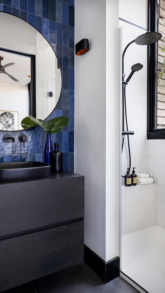 Baño con azulejos azules y mueble de lavabo negro