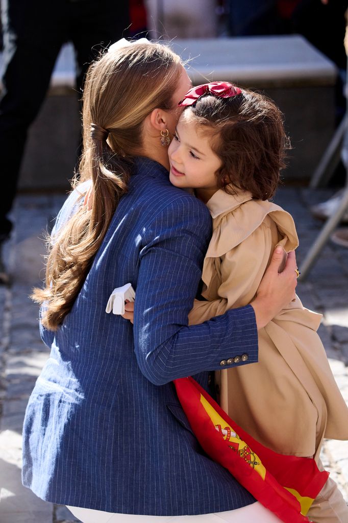 Leonor abraza a una niña que lleva en la mano una bandera de España