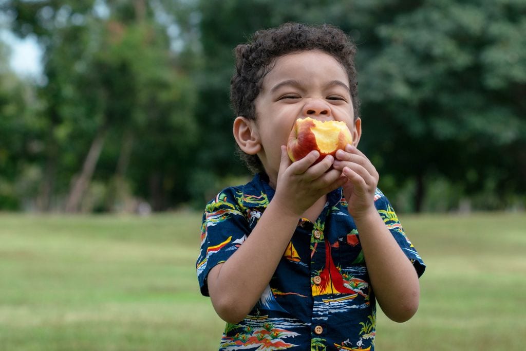 Niño tomando una fruta sin pelar