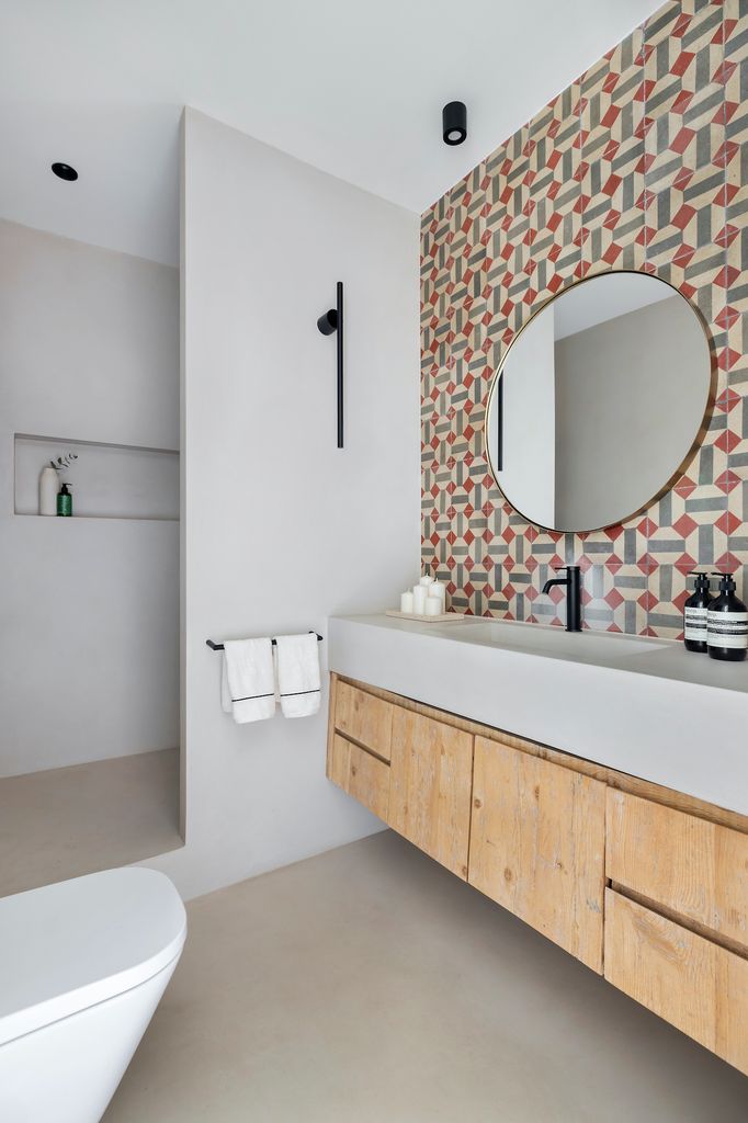 Baño con pared con revestimiento con estampado geométrico.